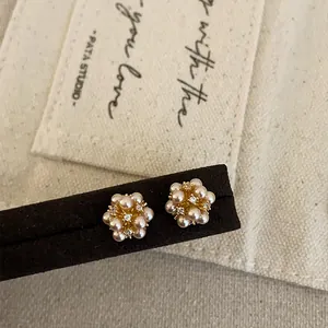 Detailed macro view of elegant pearl and rhinestone floral cluster stud earrings
