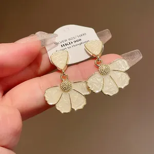 Dettaglio di orecchini a fiore in smalto bianco con centro dorato su perni in argento S925