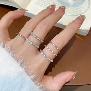 Vista dettagliata di cinque anelli minimalisti in argento e zirconi, indossati con eleganza.