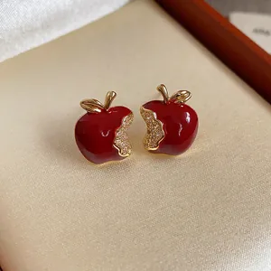 Primo piano di eleganti orecchini a lobo a mela in smalto rosso con accenti di zircone.
