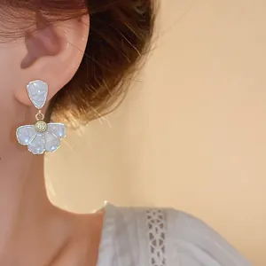 Primo piano dettagliato di un elegante orecchino a fiore bianco indossato da una modella
