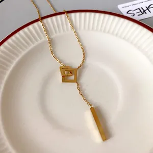 Detail of a minimalist gold geometric square pendant necklace with vertical bar.