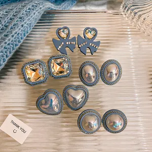 Detailed shot of vintage blue stud earrings featuring pearls and crystal heart designs.
