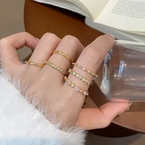 Primo piano di eleganti anelli placcati in oro con zirconi indossati sulle dita