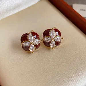 Primo piano di orecchini a lobo in smalto rosso con design floreale in zircone