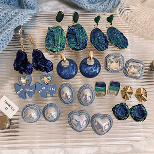 Collection of vintage blue and green earrings with pearls and crystals on glass tray