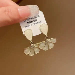 Dettaglio di eleganti orecchini a fiore in smalto bianco con finitura dorata