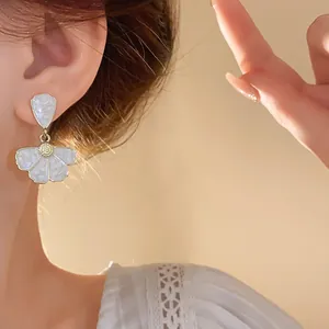 Vista dettagliata di un elegante orecchino a fiore bianco indossato da una modella