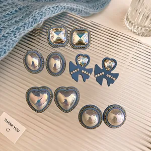 Close-up of elegant vintage blue earring set with rhinestone hearts and pearls on glass