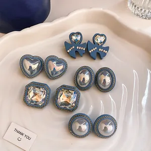 Retro dusty blue earrings collection with crystal and pearl details on a ceramic tray