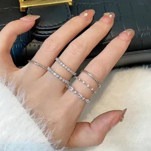 Dettaglio ravvicinato di eleganti anelli d'argento con zirconi sulle dita davanti a borsa di lusso