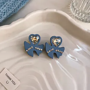 Close-up of blue heart-shaped stud earrings with sparkling crystal accents on a tray