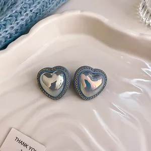 Close-up of vintage blue heart earrings with golden chain-link border detail