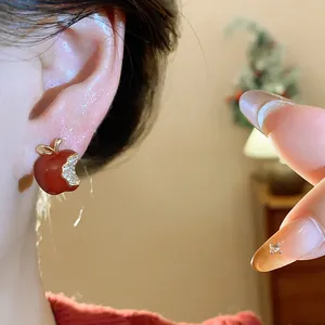 Dettaglio ravvicinato di un orecchino a forma di mela rossa con zirconi brillanti