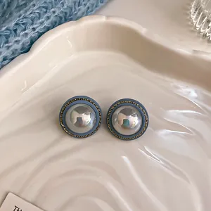 Close-up of vintage round stud earrings with blue rim and pearlescent dome