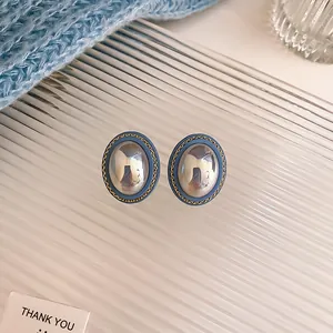 Detail shot of vintage blue oval stud earrings with metallic center and gold chain trim
