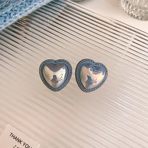 Close-up of blue iridescent heart earrings with delicate gold chain detail border