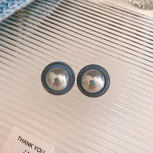 Close-up detail of vintage blue and silver round stud earrings with gold border