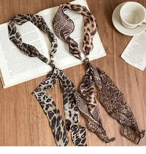 Vista dettagliata di collane in chiffon con stampe leopardate e serpente su un libro d'epoca.