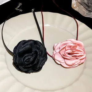 Detail of elegant black and pink fabric flower necklaces on a white plate