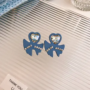 Detailed view of blue bow earrings featuring a heart-shaped sparkling rhinestone