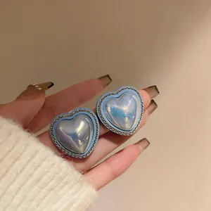 Close-up of vintage heart-shaped earrings with blue frames and iridescent centers