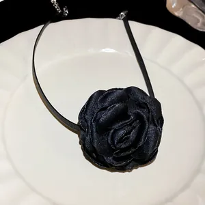 Close-up of black fabric rose choker necklace showing detailed petal texture on a white plate.