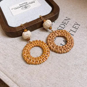 Detailaufnahme von gewebten Rattan-Creolen im Boho-Stil mit natürlichen Holzperlen