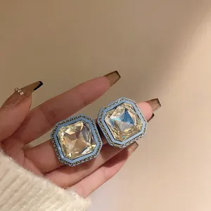 Close-up view of vintage square light blue stud earrings with large champagne crystal