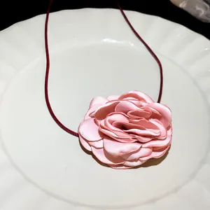 Detailed macro view of a handmade pink satin rose flower choker necklace with a red cord
