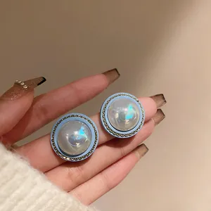 Close-up detail of light blue vintage stud earrings with iridescent pearly centers