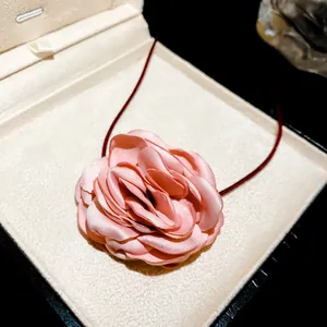 Close-up view of a sweet pink fabric rose flower choker necklace presented in a luxury gift box
