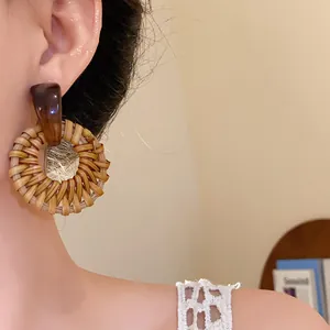 Detailaufnahme von handgewebten Rattan-Ohrringen im Boho-Stil an einem Model.