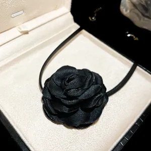 Close-up of elegant black fabric camellia flower choker necklace in jewelry box