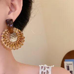 Nahaufnahme von runden Rattanohrringen im Boho-Stil, getragen am Ohr eines Models