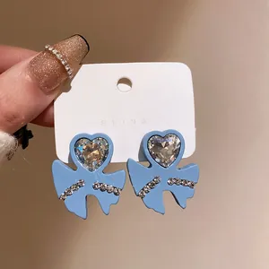 Detailed view of vintage blue bow-shaped earrings featuring a sparkling heart-shaped crystal center