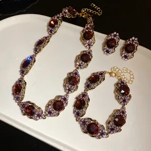 Vue détaillée d'un ensemble de bijoux vintage dorés avec pierres bordeaux et strass violets