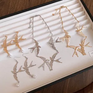 Dettaglio della collana vintage con rondine e orecchini di perle in oro e argento