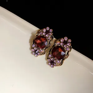 Vue détaillée de boucles d'oreilles vintage avec cristaux rouges et strass violets dorés