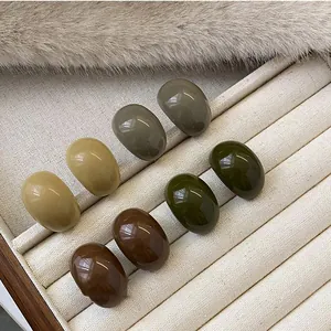 Vintage oval resin stud earrings in warm earthy tones presented in a soft jewelry box tray