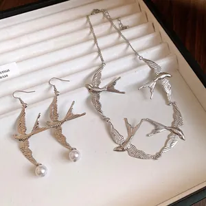 Dettaglio di un set di gioielli vintage con rondini in argento e orecchini di perle