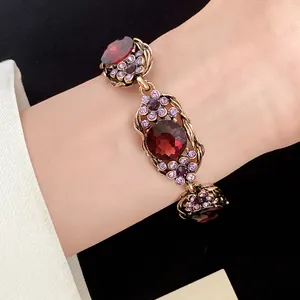 Vue rapprochée d'un bracelet vintage avec pierres rouges et strass violets au poignet