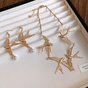 Vista dettagliata di una parure di gioielli a rondine dorati con collana e orecchini.
