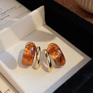 Macro view of vintage geometric hoop earrings featuring amber resin and shiny gold plating