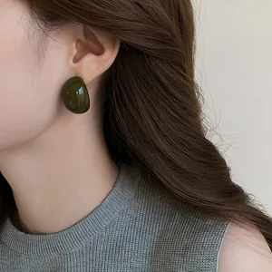 Close-up of smooth dark green resin water drop stud earring on a female ear