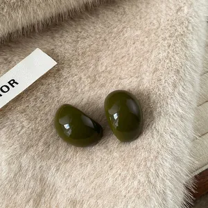 Macro view of olive green resin teardrop stud earrings against a soft fur texture