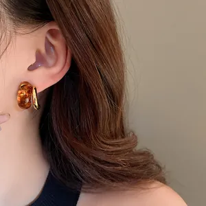 Close-up of geometric earrings with amber resin and real gold plating detail on ear