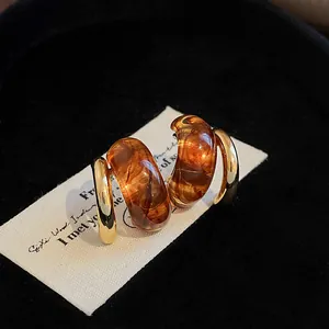 Close-up of retro geometric gold-plated earrings with amber resin detail on card