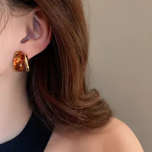 Detailed view of vintage amber resin and real gold-plated geometric hoop earrings on a model.