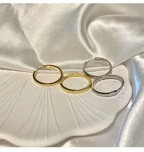 Primo piano di orecchini a cerchio in oro e argento su sfondo di conchiglia e raso bianco